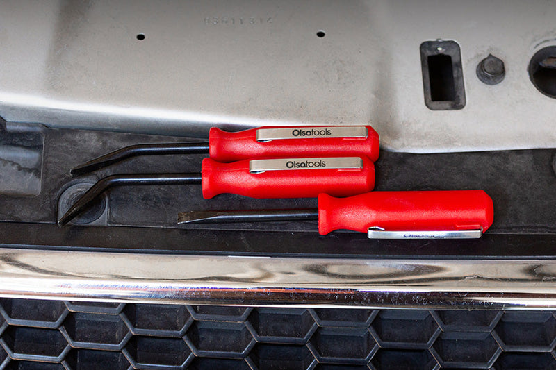 Pocket pry bars laid out on the grille of a car.